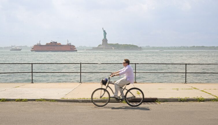 A man biking past the statue of liberty