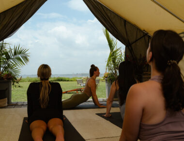 A tent full of people doing yoga looking out at the water